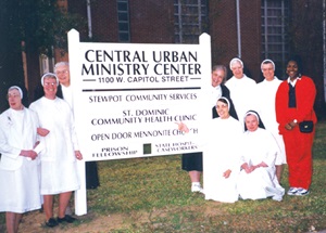 Nuns standing around ministry center sign